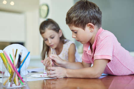 Theyre crafty kids. two adorable little siblings painting together at home.