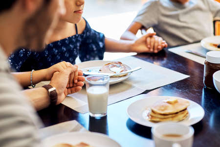 Its a blessing to be able to share this meal together. Closeup shot of a family praying before...