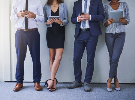 Keeping up with the pace of business. a group of unrecognizable businesspeople using wireless...