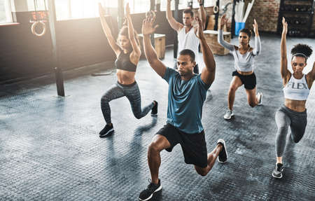 Workout with fitness minded people. a group of young people doing lunges together during their...