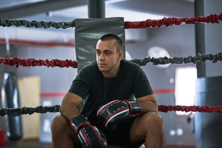 Getting familiar with the ring. a young male athlete sitting in the corner of a boxing ring.