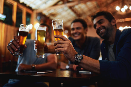 How many have we had now. a group of young friends seated at a table together while enjoying a beer and celebrating with a celebratory toast inside a bar.の写真素材