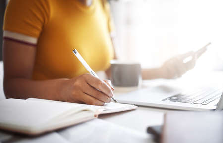 Technology is great but making a notebook is still useful. Closeup shot of an unrecognizable female...
