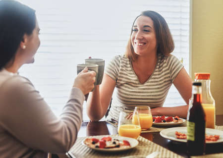 Cheers to the beginning of a beautiful day. two young women having breakfast in the morning at home.の写真素材