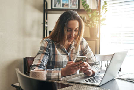 Mornings are when I check for any updates. a young woman using a laptop in the morning at home.