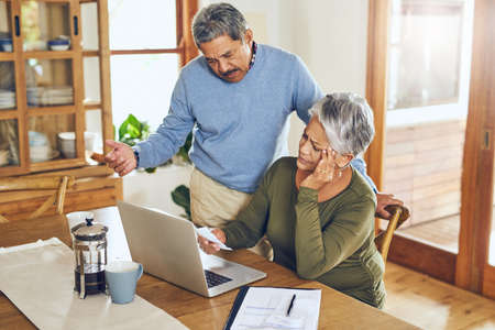 Did we really spend this much. a mature couple looking stressed out while managing their paperwork...