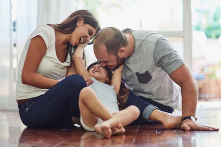 Family time is a fun time. a mother and father bonding with their adorable young daughter at home.の写真素材
