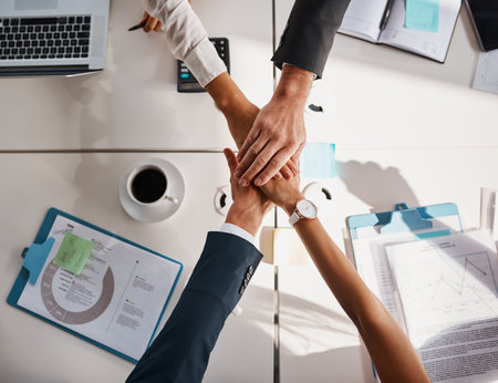 We all in this business together. High angle shot of unrecognizable corporate businesspeople joining their hands together in unity in the office.の写真素材