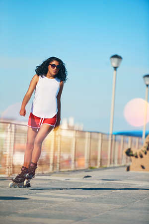 Why walk when you can skate. an attractive young woman rollerblading on a boardwalk.の写真素材