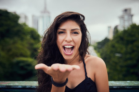 Just for you. Portrait of an attractive young woman blowing a kiss out in the city.の写真素材