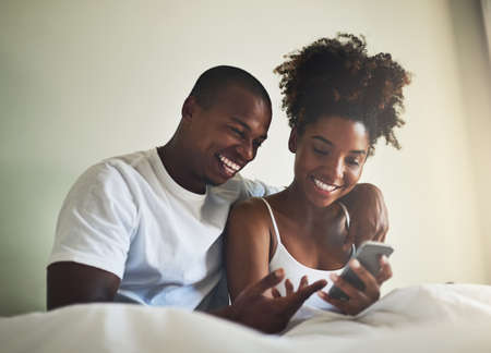 They share everything, even a social media account. a happy young couple using a mobile phone...