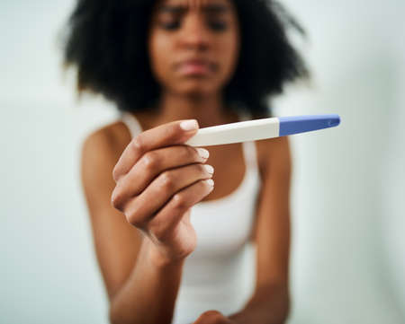 Everything is about to change. a young woman taking a pregnancy test at home.の写真素材