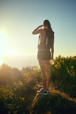 The views out here are from a hikers dream. a young woman admiring the view from the top of a mountain.の写真素材