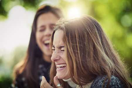 Sharing lots of laughter. two attractive young women laughing while sitting in the park.