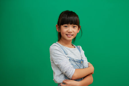 Its great being a kid. Studio portrait of confident little girl standing with her arms folded against a green background.の写真素材
