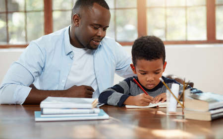 Dads here if you get stuck. a handsome young father helping his son with some homework.の写真素材