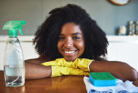 The great feeling when all my chores are done. an attractive young woman cleaning the kitchen counter at home.の写真素材