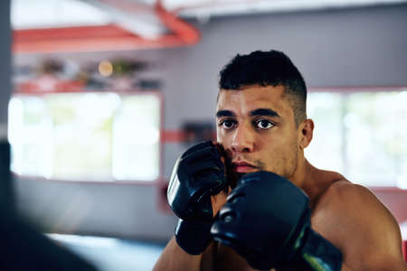 It started out as a great way to stay fit. a young man getting ready for a fight at the gym.の写真素材