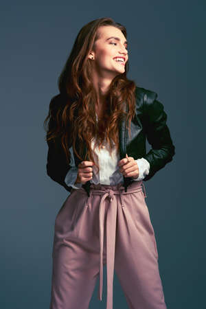 The wonders a cool jacket can do to an outfit. Studio shot of an attractive young fashionable woman posing against a blue background.の写真素材