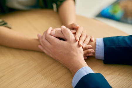 Compassion, the heart of humanity. a businessman and businesswoman compassionately holding hands at a table.の写真素材