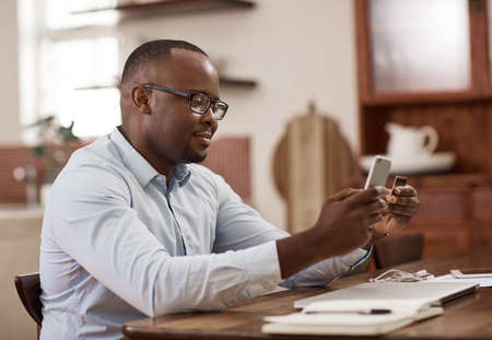 No queues, no stress. a handsome young businessman sending a text message while working at home.の写真素材