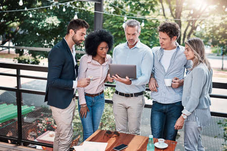 Moving their meeting outdoors for a change. a group of businesspeople working together on a laptop...