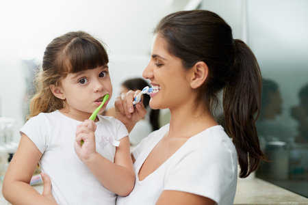This is the way we brush our teeth. Portrait of a mother and daughter brushing their teeth together in the bathroom at home.の写真素材