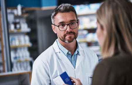 If youve got a question, hes got the answer. a mature pharmacist assisting a young woman in a chemist.の写真素材