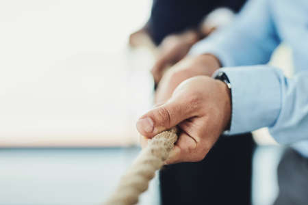 We got to pull on this rope together. Closeup of an unrecognizable businessman pulling on a rope inside of a office during the day.の写真素材