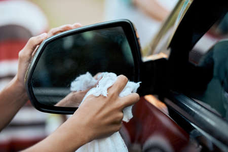Now we can see in the mirror again. an unrecognizable young child washing their parents car outside during the day.の写真素材