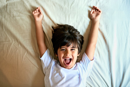 Hes an energetic little one. Portrait of an adorable little boy raising his arms while lying down on...