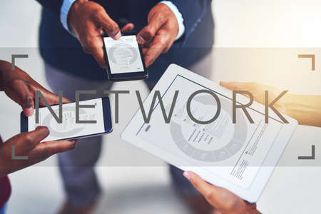 Stay connected to your business network. a group of businesspeople using wireless devices during a collaboration.の写真素材