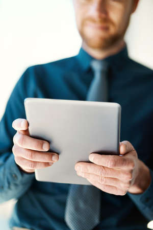 Hes always connected. an unrecognizable businessman working on a digital tablet.