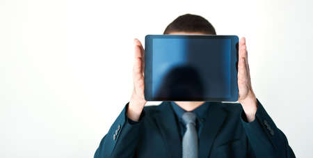 The face of modern business. an unrecognizable businessman holding a digital tablet up in front of his face.の写真素材