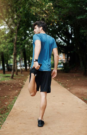 Cant stretch too much. a sporty young man stretching his legs while exercising outdoors.