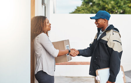 Your service never disappoints. a courier shaking hands with a customer while making a delivery.の写真素材