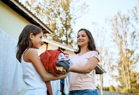 Raising a responsible young lady. a mother and daughter hanging up laundry together outside.の写真素材