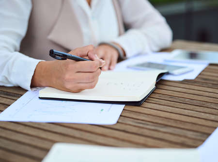 Taking extensive notes. an unrecognizable young businesswoman taking notes while sitting in her office.の写真素材