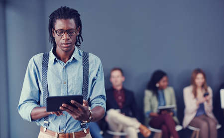 Every move is carefully calculated. a handsome young businessman using a tablet with his colleagues...