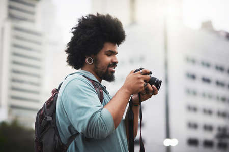 He loves capturing his city. a young man taking pictures with a camera in the city.の写真素材