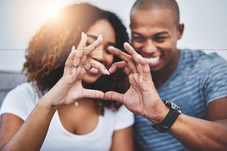Theres so much we love about each other. a young couple making a heart shape with their fingers at home.の写真素材