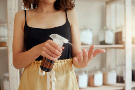 Hygiene, female spraying sanitizer on hands and helping to prevent the spread of disease by cleaning. Caucasian woman sanitizing, health and disinfecting with alcohol to clean and remove germs.の写真素材