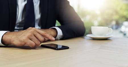 Swiping through his networks to success. Closeup shot of an unidentifiable businessman using a cellphone in an office.の写真素材