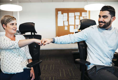 Yes we figured it out together. creative colleagues giving each other a fist pound in the office.の写真素材