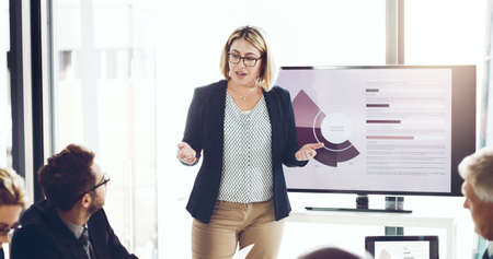 Taking them through the information. an attractive young businesswoman giving a presentation in the...