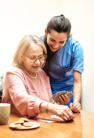 Youre better than you thought. a female nurse teaching her patient how to play a card game.