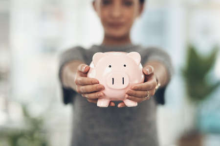 Piggybank, finance and money in the hands of a woman with a mindset on the future for saving, investment and wealth. Closeup of a coin bank in hand, showing financial growth, planning and budgetの写真素材
