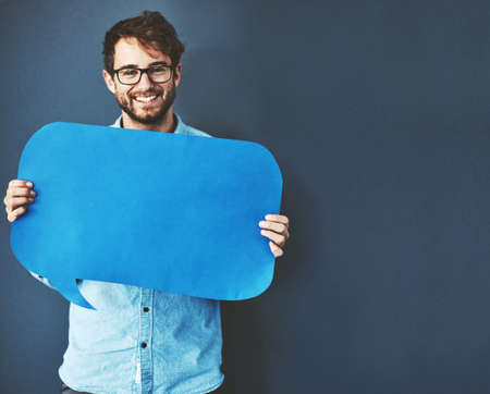 Let your thoughts be seen. Studio portrait of a young man holding a speech bubble against a grey...