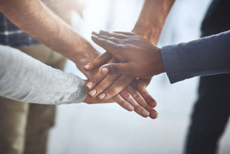 Lets give it our all. Closeup shot of a group of unidentifiable businesspeople joining their hands...
