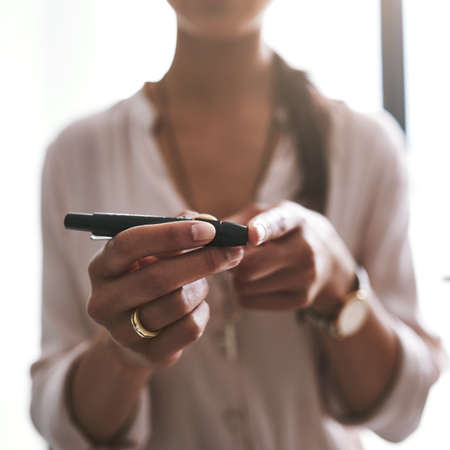 Managing her health. Closeup shot of an unidentifiable businesswoman testing her blood sugar level in an office.の写真素材